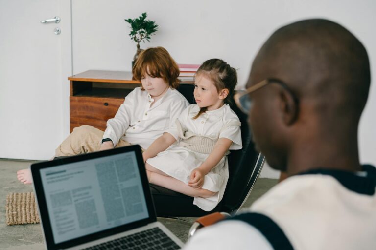 Therapist working with two children in an indoor therapy session, focusing on mental health.